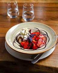 Mozzarella and burrata salad in a bowl, glasses of water on wooden table