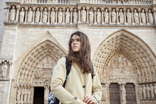 Young sensitive woman tourist standing in front of the famous Notre Dame cathedral in Paris