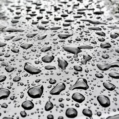 Transparent drops of water on a glossy black surface.