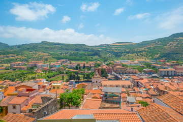 Panorama of the colorful town of Bosa along a river and hills in sunlight in spring