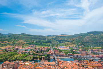 Panorama of the colorful town of Bosa along a river and hills in sunlight in spring