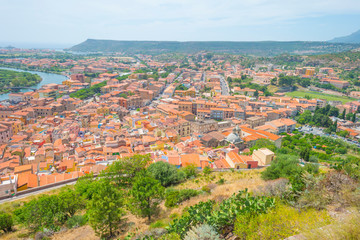 Panorama of the colorful town of Bosa along a river and hills in sunlight in spring