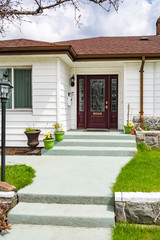 Main entrance of nice family house with doorsteps and pathway through green lawn