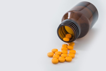 Medical pills spilling out of a toppled from pill bottle