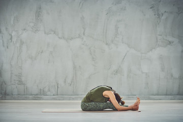 Beautiful Caucasian brunette doing yoga on mat. Caterpillar pose.