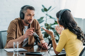 two radio hosts talking and gesturing while recording podcast in radio studio
