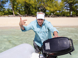 Naklejka premium Older man pushing his dinghy out to get it started off the beach 