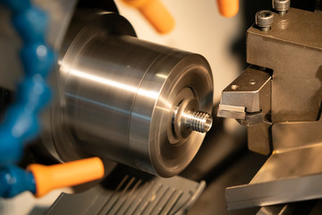 The CNC lathe machine cutting the thread at the steel shaft. The modern part manufacturing process.