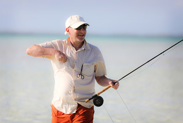 Older man bone fishing in the Bahamas walking through the water. 