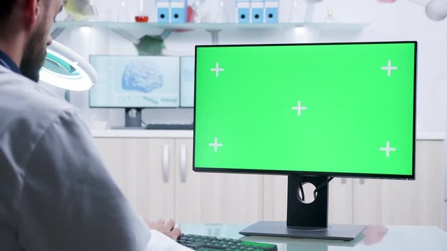 Over the shoulder shot of scientist working on green screen computer in modern high end laboratory