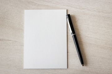 Blank notepad and pen on wooden table.