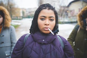 young african woman posing outdoor in the street and smoking cigarette