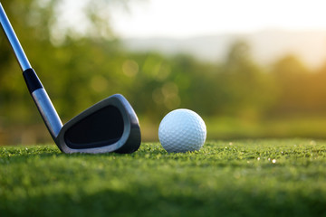 Golf clubs and golf balls on a green lawn in a beautiful golf course
