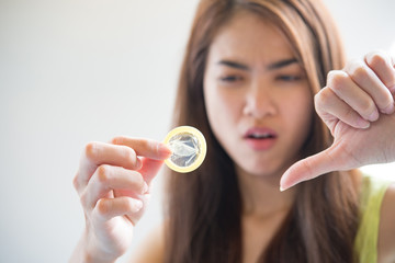 Young woman holding condom prevent pregnancy