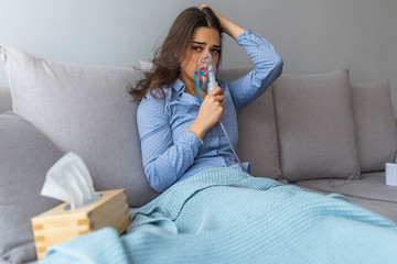 Nebulizer aerosol woman inhaler machine medicine at home. Portrait of a young woman doing...