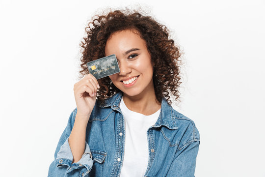 Happy young african woman posing isolated over white wall background holding credit card.