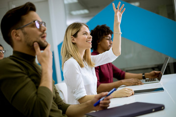 Woman raised her hand up for question in conference meeting