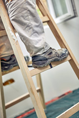 Worker standing on the ladder and renovating house.