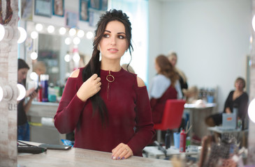 Woman in a beauty salon looks at her reflection in the mirror on her makeup and hairstyle.
