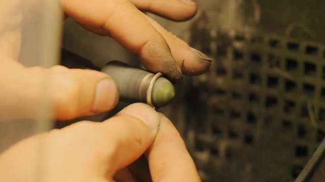 Jewerly master works with a small rotating circular saw for grinding the inner edge of a metal ring and the crown slow motion