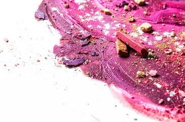 Artistic lipstick smudge and crushed eyeshadow as background