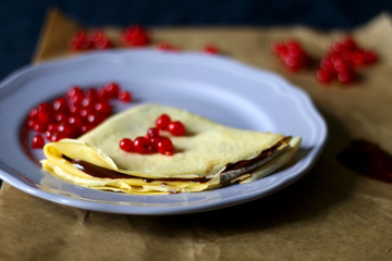 Homemade crepes with chocolate spread and red currants. Selective focus.