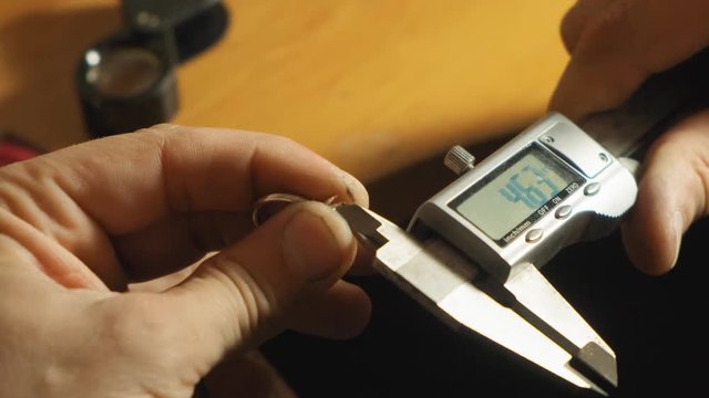 Jewel master measured the size of gemstone for a rin close up view slow motion