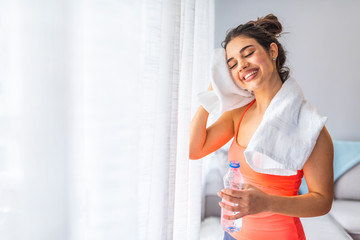 Muscular woman taking break after exercise. Smiling attractive fitness woman with towel after training. Jogger run runner energy sweaty yoga vitality wellness concept