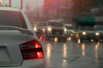 Blurred image from rainy season. The back of the white car parked on the traffic signal and there...