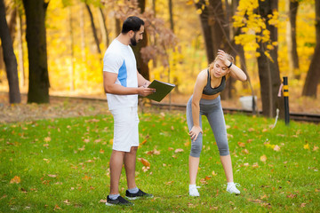 Fitness. Personal Trainer Takes Notes While Woman Exercising Outdoor