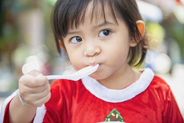  little girl  eating food with a plastic spoon.