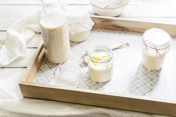 Vegan panna cotta dessert and almond milk in glass jars on a breakfast tray on white wooden rustic background