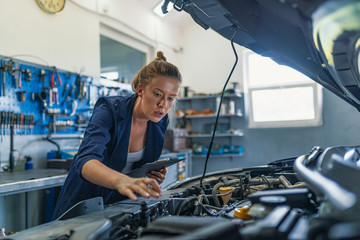 Female mechanic working on car. A Mechanic woman working on car in her shop. Technician woman...