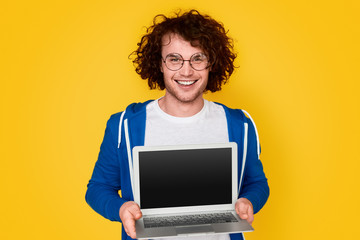 Fototapeta na wymiar Cheerful nerd showing blank laptop