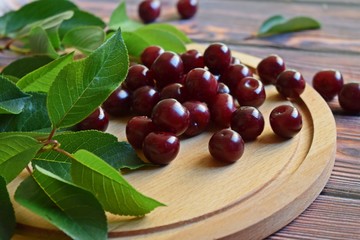 Fresh,sweet cherry berries and green leaves on wooden background.