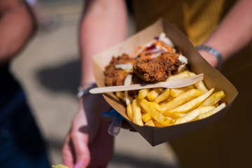 Person holding a tray of Fried chicken and chips in a food festival