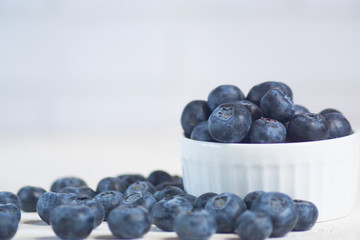 close up of bowl with blueberries on white concrete background