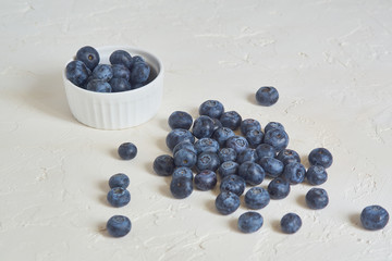 close up of bowl with blueberries on white concrete background