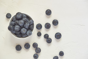 Top view of bowl with blueberries on white concrete background