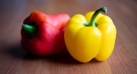 Yellow and red peppers on wooden table at home