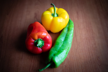 Green, yellow and red peppers on wooden table at home