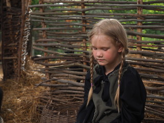 Emotional portrait of a child. The village girl with pigtails is sad. Old fence