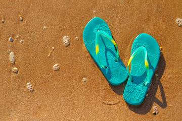 Fototapeta na wymiar women's flip flops stand on the beach on the sand, vacation concept