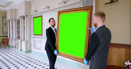 Scientific officers of art gallery hanging picture on wall