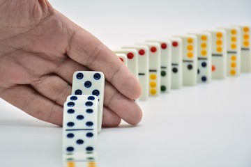 Mano cortando la caída en serie de fichas de dominó