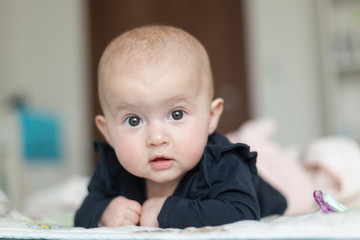 Naklejka premium Portrait of a charming baby lying on its stomach. Family morning at home. Tummy time