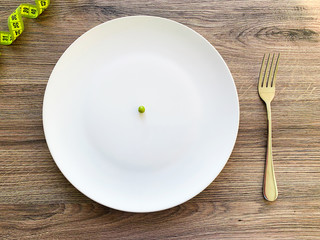 Cropped image pea on white plate, with fork and measuring