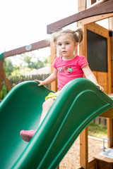A cute young kid playing on a slide in a park	