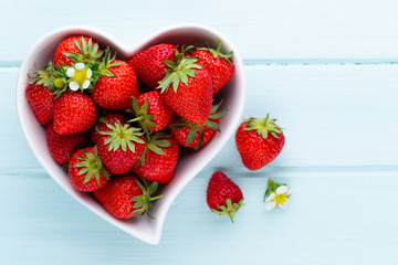 Strawberry heart. Fresh strawberries in plate on white wooden table. Top view, copy space.