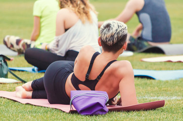 young girl lying on a yoga mat in the park with a group of people